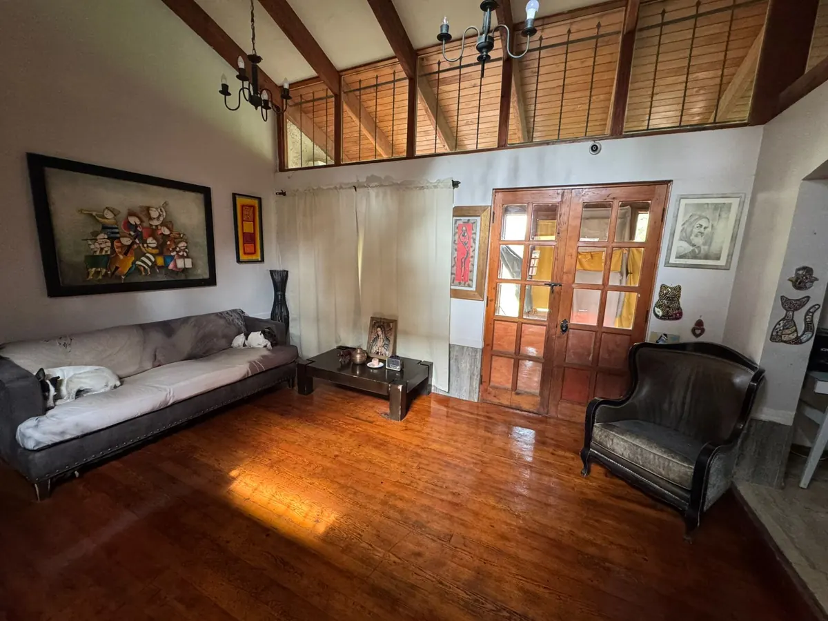 Interior de la casa con piso de madera, sillones y un perro descansando